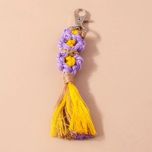 Detailed macro view of handmade woven flower keychain with purple tassels and metal lobster clasp
