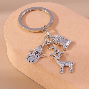 Macro shot of silver Christmas keychain charms featuring a snowman, reindeer, and stocking