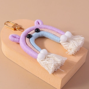 Macro shot of handmade woven rainbow keychain with purple tassels and gold lobster clasp