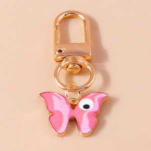 Détail du porte-clés papillon en émail rose avec motif œil et fermoir mousqueton doré
