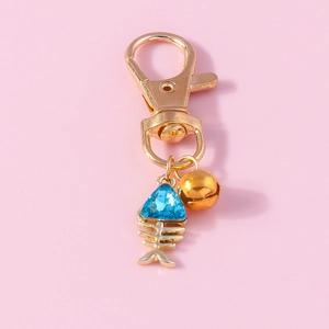 Detailed view of fishbone pendant with blue gemstone and bell on a golden keychain