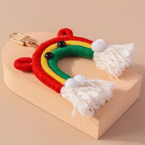 Detail of handmade woven rainbow keychain with white tassels and plush pom-poms charms
