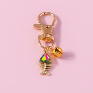 Close-up of golden fishbone keychain with iridescent rhinestone and small bell