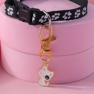 Détail d'un collier pour chat avec motifs de pattes et pendentif en émail sur fond rose