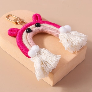 Detailed shot of handmade rainbow keychain with pink tassels and white cotton pom-poms