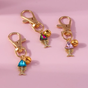 Close-up of golden fishbone keychains with colorful crystal heads and small bells