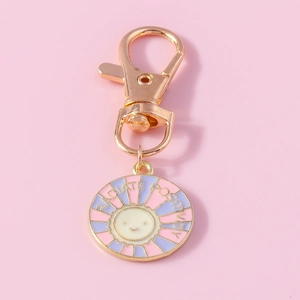 Detail of rose gold keychain with enamel sun charm and 'Radiate Positivity' engraving