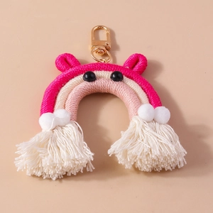 Detailed macro view of a handmade woven rainbow keychain with white tassels and gold clasp