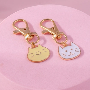 Close-up of yellow and white cute cat charms with lobster clasp on pink display