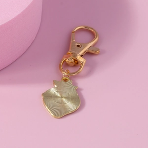 Creative strawberry cat pendant keychain in gold finish on pink background