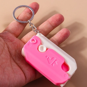 Close-up of pink and white mini utility knife keychain held in hand for size display