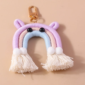 Detail of handmade rainbow keychain with colorful cotton cords, white pompoms, and tassels