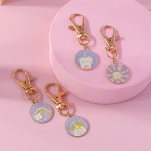 Detailed view of four colorful enamel pet keychains with golden lobster clasps on pink background