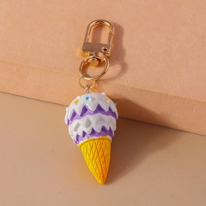 Close-up of a resin ice cream keychain with purple white scoops and gold metal hook