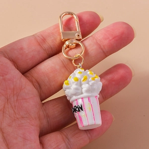Macro shot of a popcorn keychain featuring a pink striped bucket and golden lobster clasp