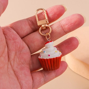 Nahaufnahme eines Cupcake-Schlüsselanhängers mit roter Basis und bunten Streuseln auf Creme