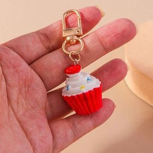 Detail eines Cupcake-Schlüsselanhängers mit rotem Herz, in der Hand einer Person