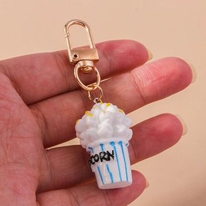 Detail shot of a cute popcorn bucket keychain with gold metal clasp held in hand