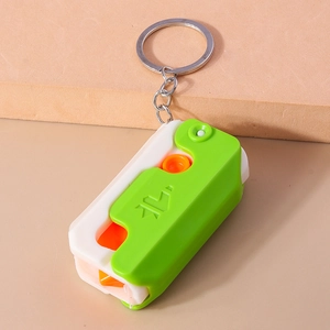 Close-up of a portable green and white pill cutter keychain with orange plastic components