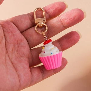 Detail eines Cupcake-Schlüsselanhängers mit rosa Basis, weißem Guss und Goldverschluss