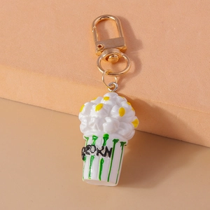 Close-up of a creative popcorn keychain with a gold lobster clasp and resin details