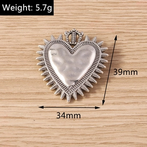 Macro shot of silver heart charm with crown detail, showing 39mm x 34mm size and 5.7g weight
