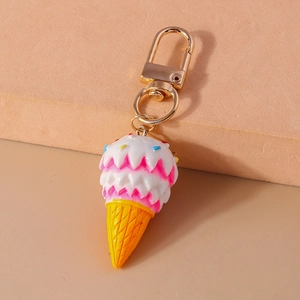 Close-up of pink and white ice cream cone keychain with gold metal clasp on pink background
