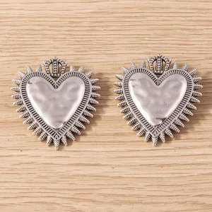 Vintage silver heart charms with crown detail and textured finish on wooden background