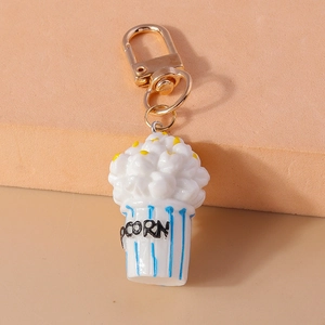 Close-up of cute popcorn keychain with striped blue cup and golden metal carabiner