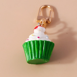Nahaufnahme eines bunten Cupcake-Schlüsselanhängers mit goldenem Verschluss auf Beige