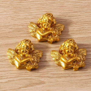 Three golden angel resin charms with harp relief detail on a rustic wooden background