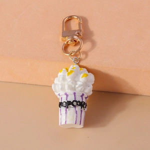 Detailed view of a mini popcorn keychain with gold metal clasp and purple striped cup