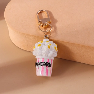 Close-up of cute popcorn keychain with pink stripes and golden metal lobster clasp