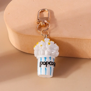 Close-up of a creative popcorn keychain with a golden metal clasp and blue striped bucket