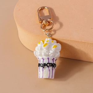 Close-up of cute popcorn keychain with purple stripes and a gold metal clasp