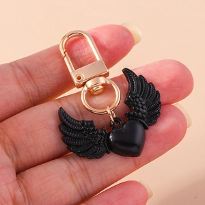 Gros plan sur un porte-clés cœur noir avec ailes et fermoir mousqueton doré