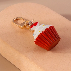 Detailansicht eines rot-weißen Cupcake-Schlüsselanhängers mit goldenem Metallkarabiner