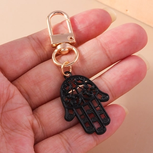 Détail macro du porte-clés main de Fatima avec motifs évidés noirs et fermoir en métal doré