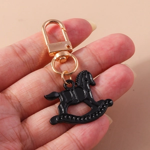Détail d'un porte-clés cheval à bascule noir avec un fermoir à ressort en métal doré