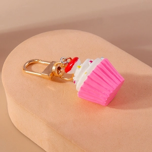 Detaillierte Makroansicht eines rosa Cupcake-Schlüsselanhängers mit weißer Creme und Karabiner