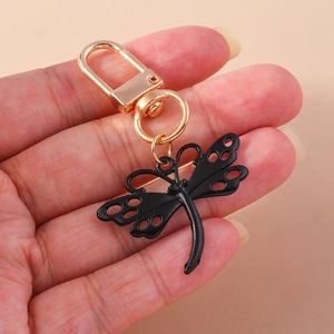 Détail du porte-clés libellé noir et doré tenu par la main pour montrer la taille et l'éclat