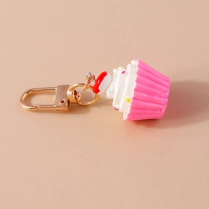 Detail eines realistischen rosa Cupcake-Schlüsselanhängers mit Perlen und Goldkarabiner