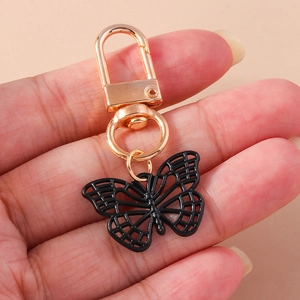 Détail d'un pendentif papillon noir évidé avec fermoir doré tenu à la main