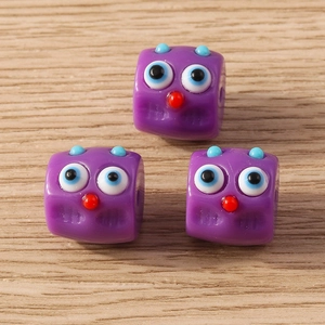 Macro view of purple cartoon monster resin beads with large eyes for DIY jewelry