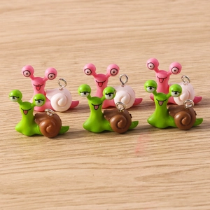 Detail of colorful mini snail charms with metal loops on a light wood background