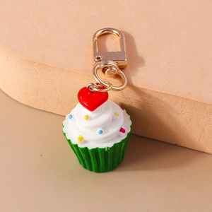 Draufsicht auf Cupcake Schlüsselanhänger mit weißer Creme, grüner Basis und rotem Herz