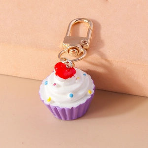 Nahaufnahme eines Cupcake-Schlüsselanhängers mit lila Basis und goldenem Federhaken