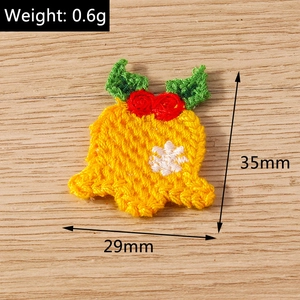 Detailed macro of a yellow knit Christmas bell patch with red rose embroidery