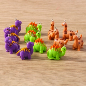 Close-up of colorful resin dinosaur charms with silver rings on a wooden surface