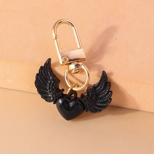 Détail du porte-clés cœur à ailes noires gothique avec fermoir doré sur fond orange doux